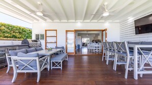 An outdoor patio with wooden furniture, a grill, and ceiling fans. - Barronstown - Pet Friendly with Fire Pit (Callala Beach)