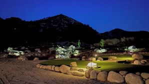 A nighttime golf course with illuminated rocks and a well-maintained putting green. - Beautiful Blossom Creek Suite (Three Rivers)