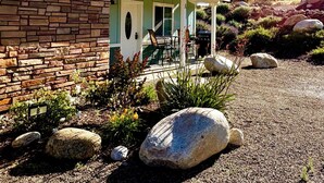 A stone building with a covered patio, outdoor seating, and a garden with rocks and plants. - Beautiful Blossom Creek Suite (Three Rivers)