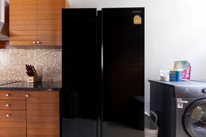 Uma cozinha com geladeira preta, máquina de lavar e armários de madeira.