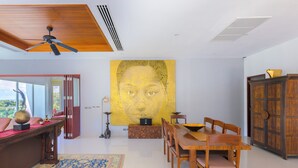 A dining area with a wooden table and chairs, a large yellow artwork on the wall, and a traditional cabinet. - The Villa In The Sky: Luxurious Abundance, Breathtaking Views, Premier Comfort (Kathu)