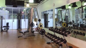 Une salle de sport équipée de divers appareils de musculation, de miroirs et dotée d’un plancher en bois.