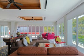 A spacious living room with a large window, a ceiling fan, and a red chair.