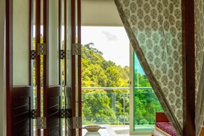 A room with a view of a balcony and a window with patterned curtains.