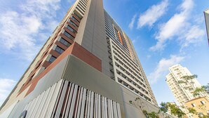 Un edificio de gran altura con diseño arquitectónico moderno, que destaca por una estructura vertical y varios balcones.