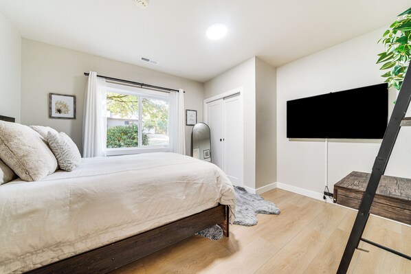 A bedroom with a bed, a window with curtains, a television on a stand, and a plant. - 13 Mi to Lumen Field & Dtwn Seattle! Cozy Retreat (Newcastle)