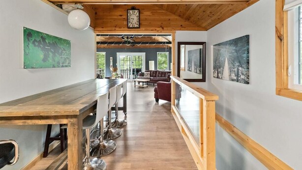 A spacious kitchen with a wooden ceiling, a long counter with bar stools, and a view of the dining area. - Charming Cottage on the Lake - Family and Pet Friendly (LaBelle)