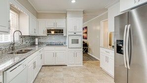 A modern kitchen with white cabinets, granite countertops, stainless steel appliances, and a tiled backsplash. - 3 Mi to Arabia Mtn Trails: Quiet Ranch-Style Home (Stonecrest)