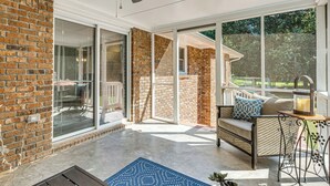 A sunlit patio with a brick wall, sliding glass doors, a cushioned outdoor seating area, and a ceiling fan. - 3 Mi to Arabia Mtn Trails: Quiet Ranch-Style Home (Stonecrest)