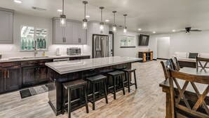 Una cocina moderna con una isla grande, taburetes de bar y un comedor con mesa y sillas.
