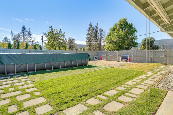 A backyard with a green lawn, stone stepping stones, a covered area, and a view of trees and hills. - Backyard Oasis w/ Hot Tub & Views: Weaverville Gem (Weaverville)