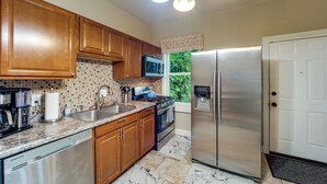 A kitchen with wooden cabinets, a stainless steel refrigerator, a stove, and a dishwasher.