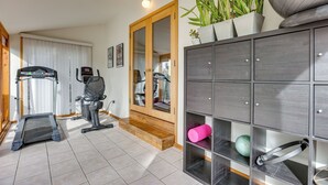 A home gym with a treadmill, exercise bike, and weights, a wooden door, and a mirrored closet with shelves. - Next to 600 Acres of Public Land! Bend Ranch Home (Bend)