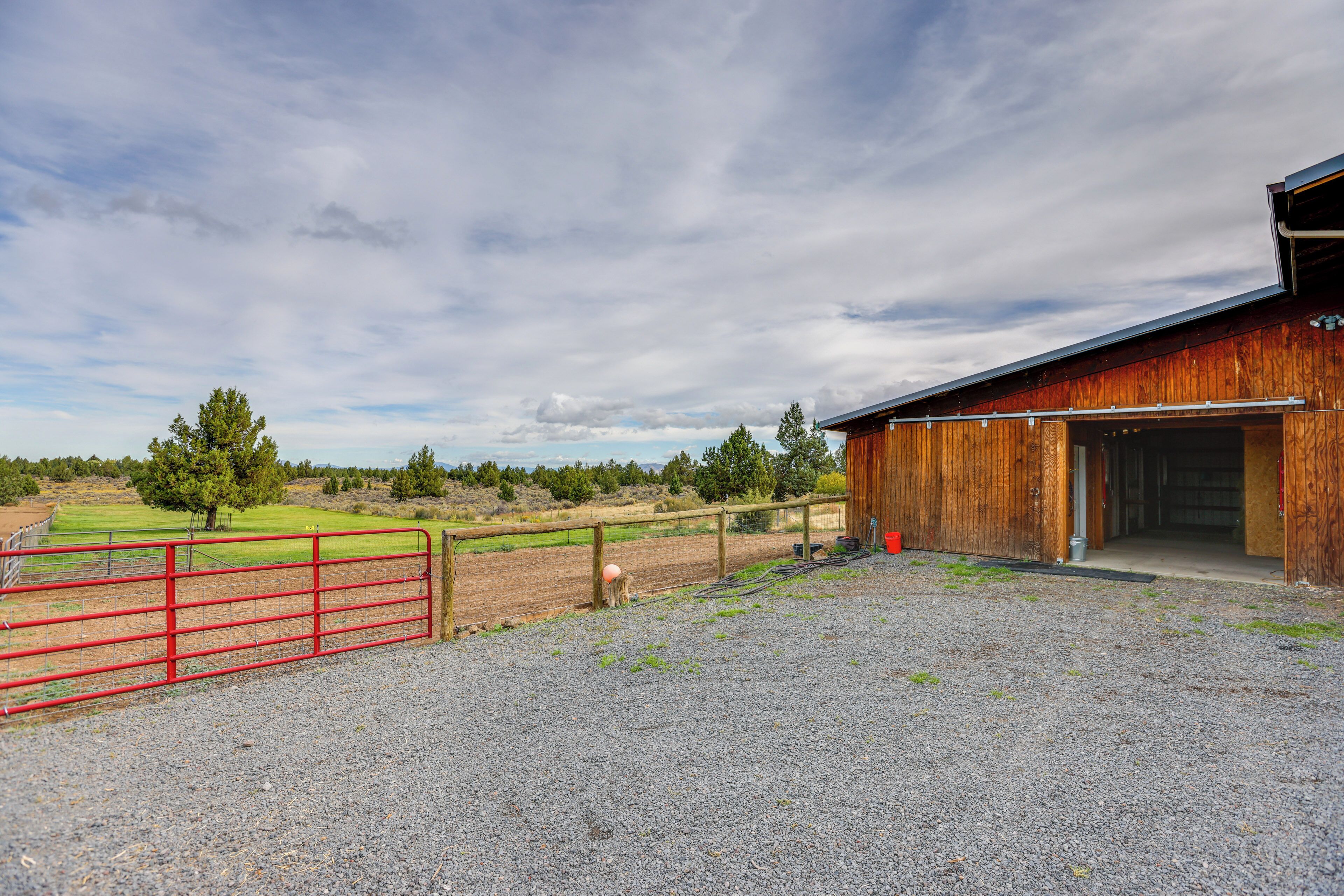 A barn with a gravel driveway and a red gate.