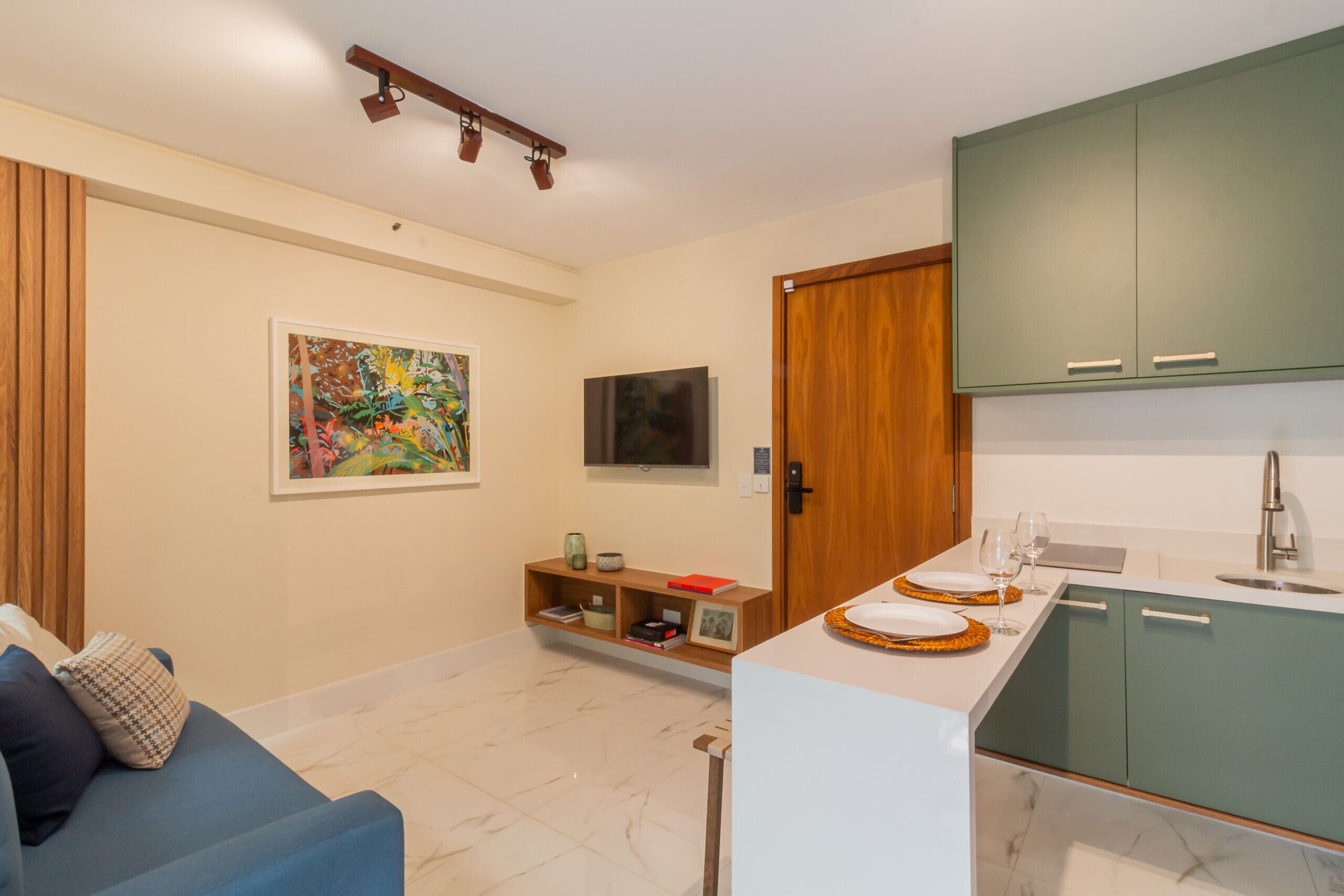 Un salon moderne avec un canapé bleu, un téléviseur fixé au mur et une porte en bois.