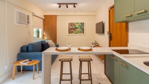 A modern kitchen with a central island, bar stools, a blue sofa, and a painting on the wall. - 6 Minutes From Leblon Beach Gsm103 (Rio de Janeiro)