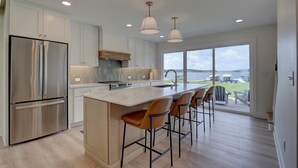 Una cocina moderna con una isla grande, electrodomésticos de acero inoxidable y vistas al exterior.