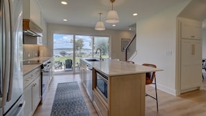 Una cocina moderna con armarios blancos, una isla grande y vistas al exterior.