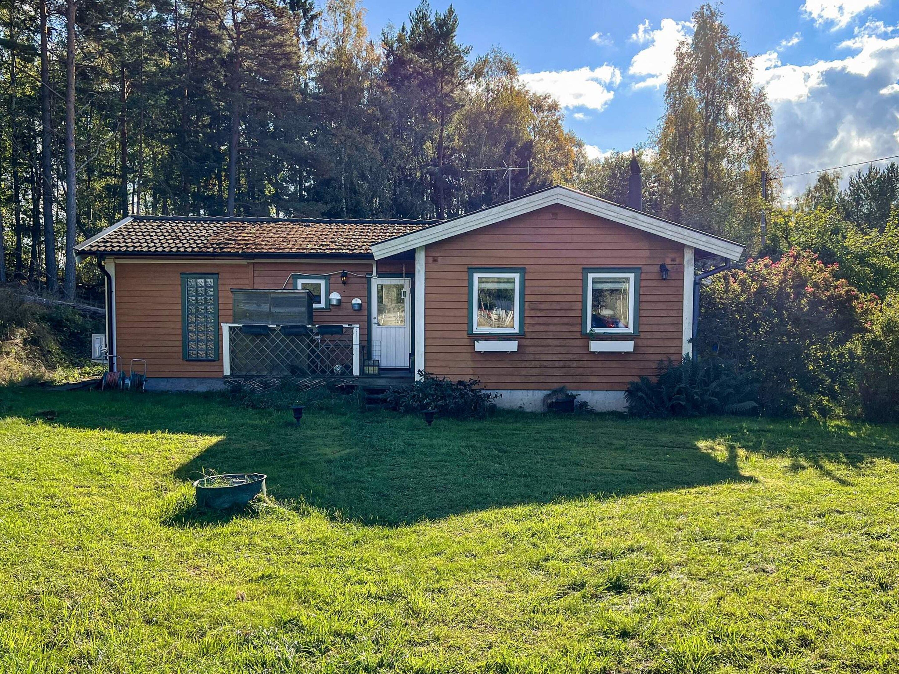 A two-story house with a red-tiled roof, a front porch, and a well-maintained lawn.