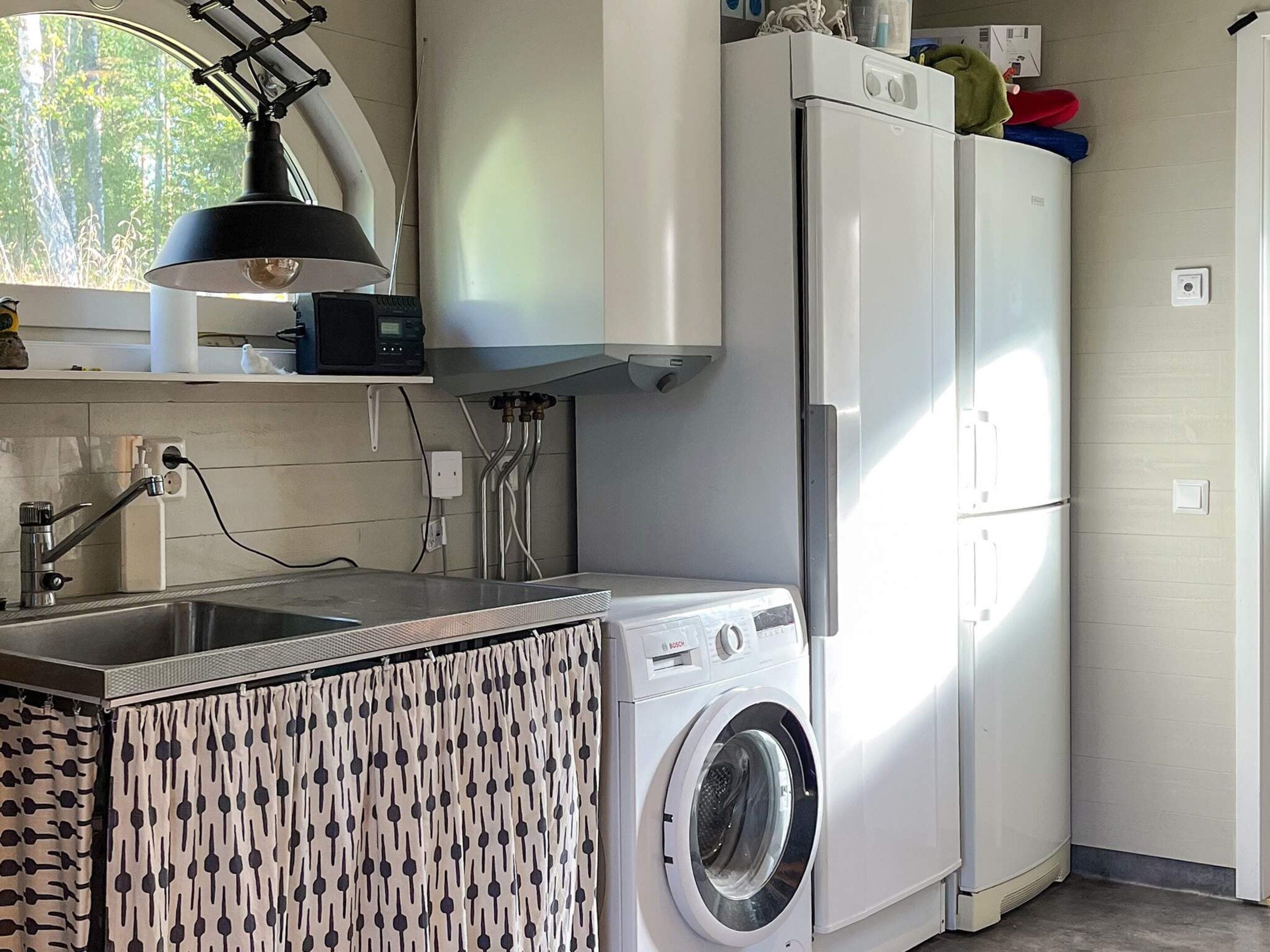 A kitchen with a washing machine, a sink, and a microwave.