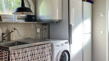 A kitchen with a washing machine, a sink, and a microwave.
