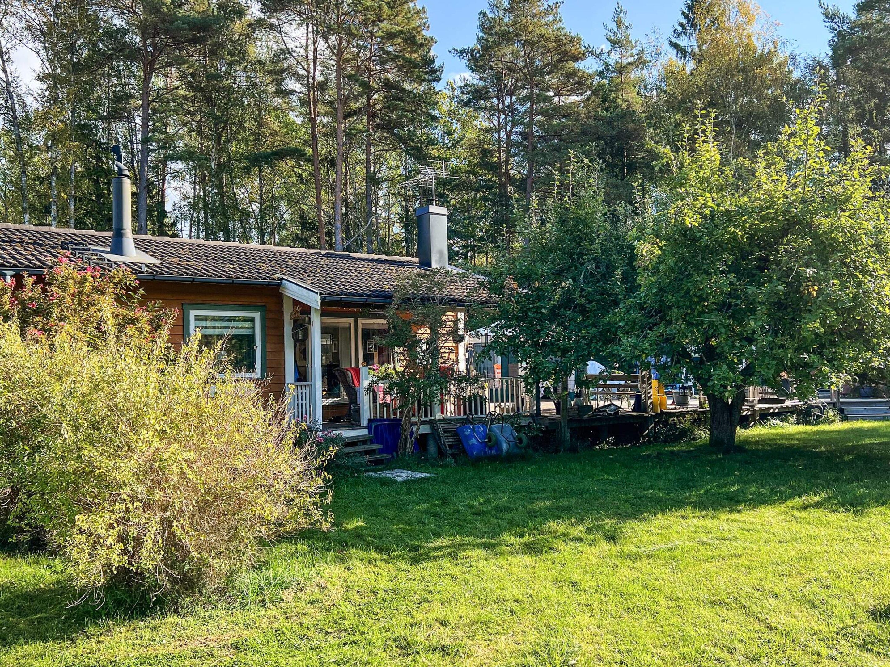 A house with a porch, surrounded by trees and a grassy yard.