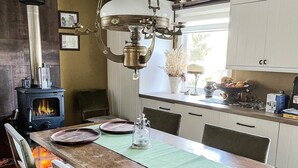 A kitchen with a wood-burning stove, a chandelier, and a dining table set for two. - 5 Person Holiday Home in Adelso (Adelso)