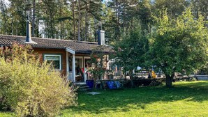 A house with a porch, a chimney, and a yard with trees and grass. - 5 Person Holiday Home in Adelso (Adelso)