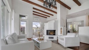 Een moderne woonkamer met witte meubels, een open haard en zichtbare houten balken.