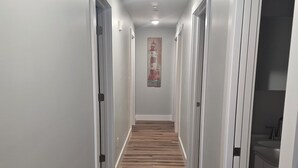 A hallway with wooden flooring, white walls, and doors leading to rooms. - 3-bedroom Condo 5141 A Bellaire (Bellaire)
