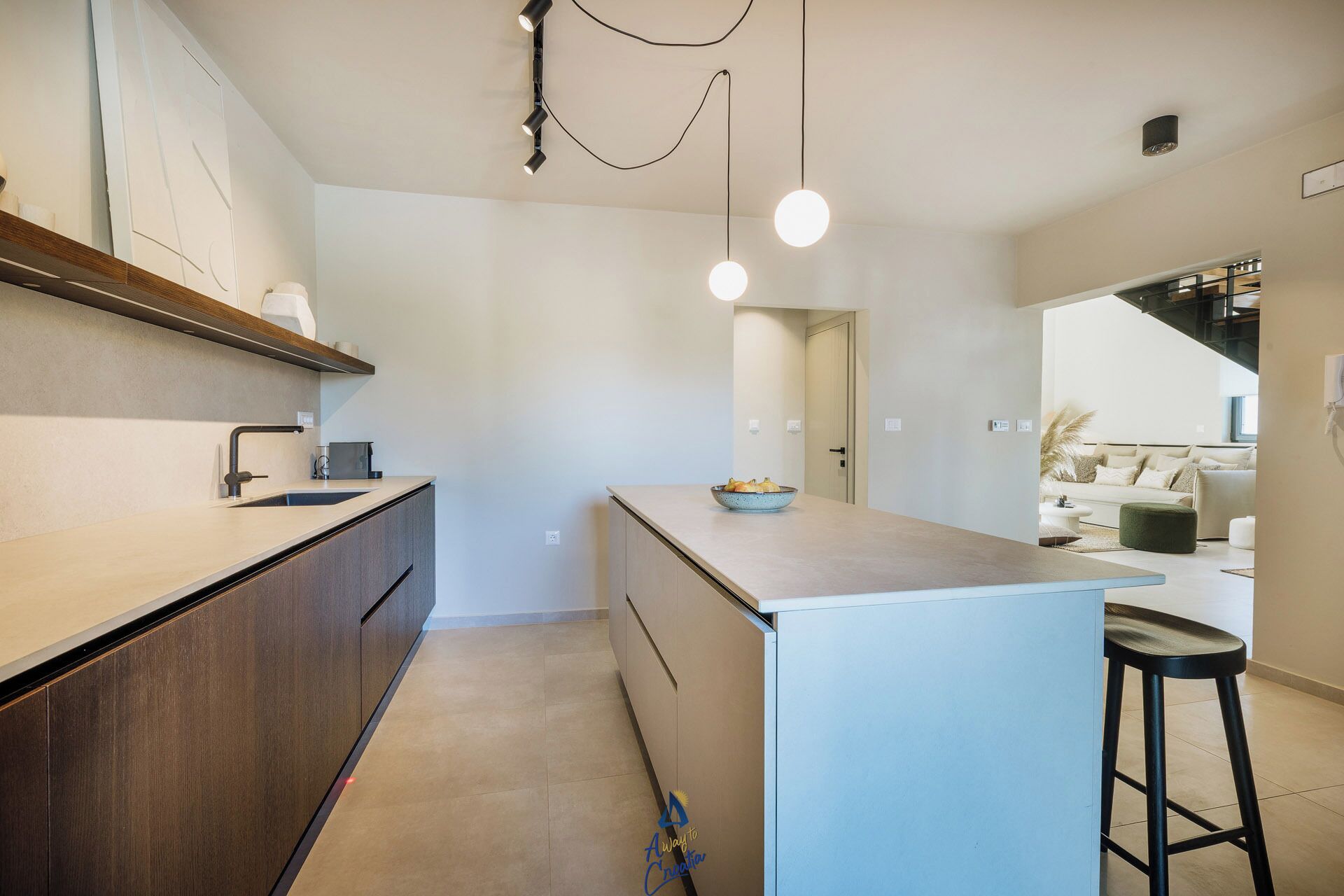 A modern kitchen with a central island, a built-in oven, and a bar stool.