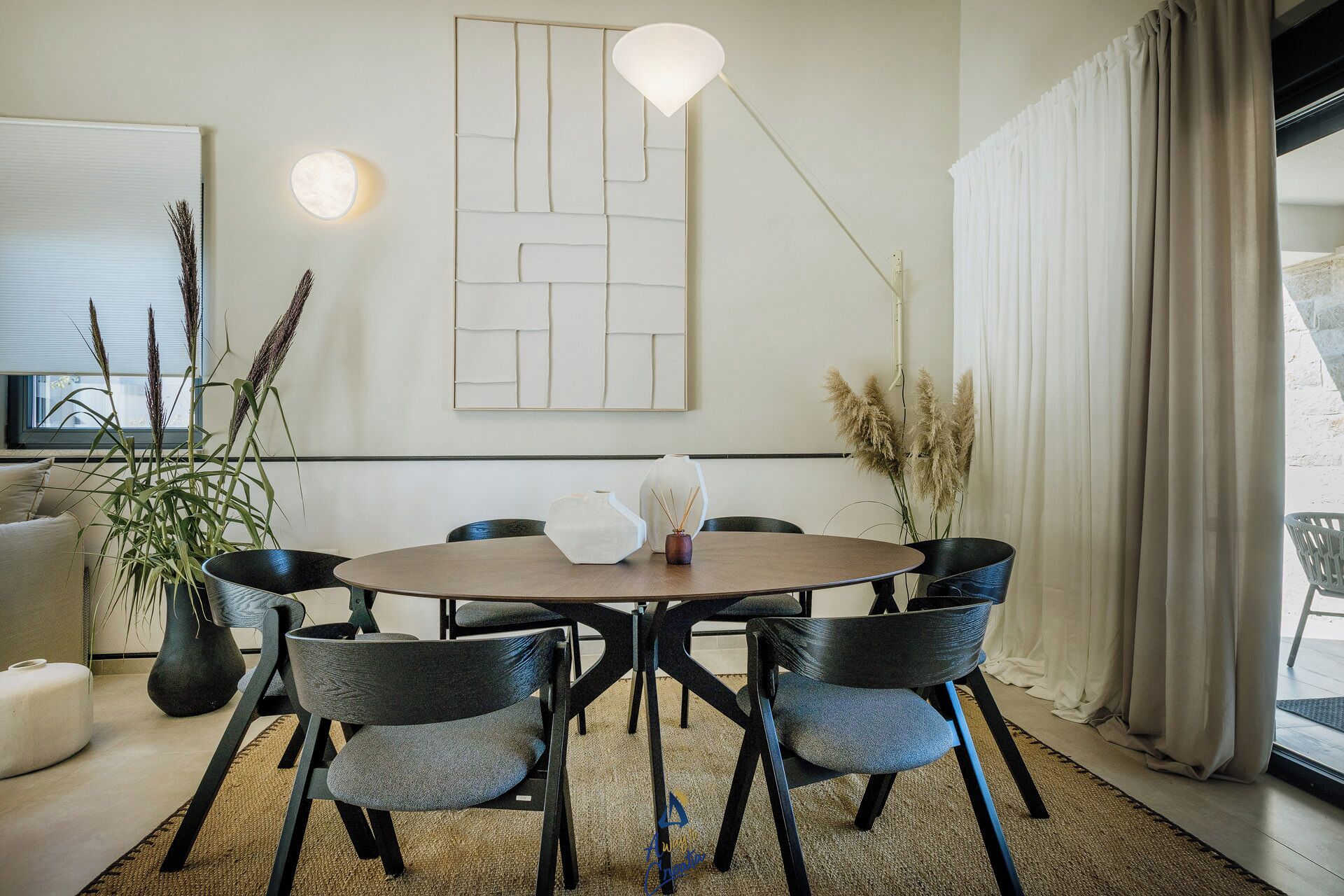 A modern dining area with a round table, six chairs, and a minimalist wall art piece.