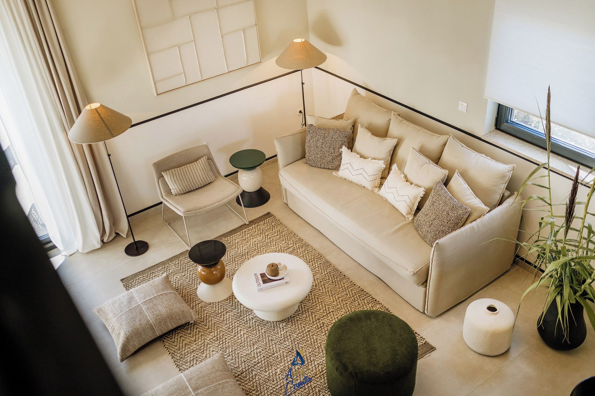 A modern living room with a beige sofa, two side tables, a coffee table, and a patterned rug.