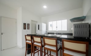 A modern kitchen with a dining area, white walls, and a large window. - Fully Equipped Apartments in a Condo With a Pool, 750m From the Beach - Vifs (Porto Seguro)