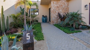 A pathway leading to a building with a stone wall and a number '5' sign. - Escape to Cabo Luxury at Las Terrazas #05 (Cabo San Lucas)