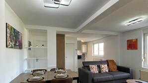 A modern living space with a dining area, a gray sofa, and a small round table.