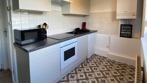 A modern kitchen with white cabinets, a microwave, a coffee maker, and a patterned floor.