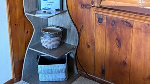 A wooden interior with a curved shelving unit holding a welcome sign, a framed picture, and baskets. - Lakeshore Cottage, For Outdoor Enthusiasts (Gaylord)