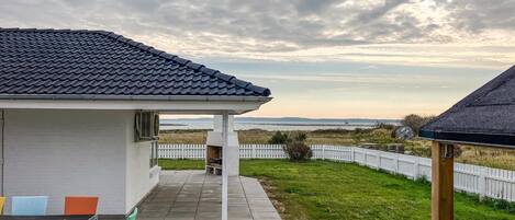 Une terrasse avec mobilier d’extérieur, un espace salon abrité et une vue sur la mer.