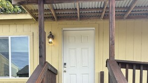 Un escalier en bois mène à une porte blanche surmontée d’une caméra de surveillance.