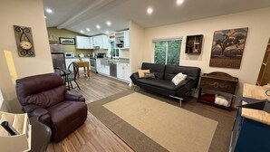 Un salon moderne avec un canapé en cuir marron, un canapé noir et un coin repas comprenant une table et des chaises en bois.