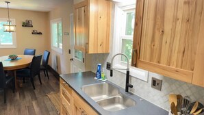 Une cuisine dotée de meubles en bois, d  ’un évier à deux bacs et d’un coin repas avec une table et des chaises.