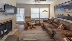 A living room with a fireplace, a sofa, a chair, and a painting on the wall.