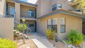 A modern multi-story residential building with a central staircase, balconies, and a small garden area.