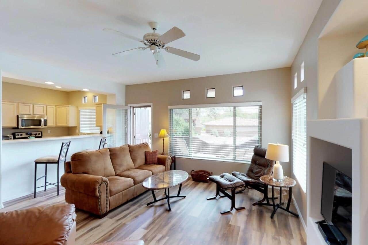 A spacious living room with a sofa, coffee table, and chairs, a kitchen area with cabinets and appliances, and a fireplace.
