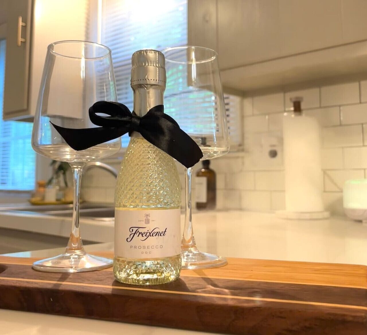 Pullo Freixenet Prosecco DOC -kuohuviiniä puisen tarjottimen päällä, tarjottimella on myös kaksi viinilasia.