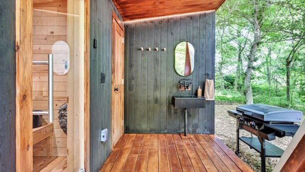 Eine Holzhütte mit einer Holzterrasse, einem Grill und einem Spiegel an der Wand.