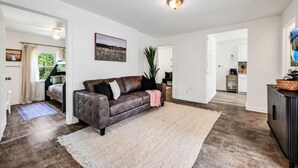 A spacious living room with a dark brown leather sofa, a large rug, and a ceiling light fixture.