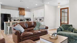 Un salon moderne avec un canapé en cuir marron, un fauteuil vert et une table basse en bois.