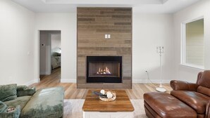 Un salon moderne avec une cheminée, un plancher en bois et des meubles en cuir.